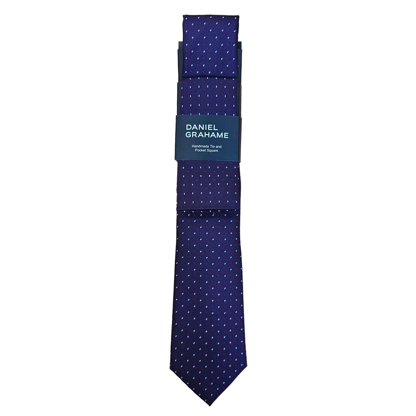 A dark purple necktie with a small pattern, folded with its paper band tag, placed on a light wood grain surface. The tag reads 'DANIEL GRAHAME'.