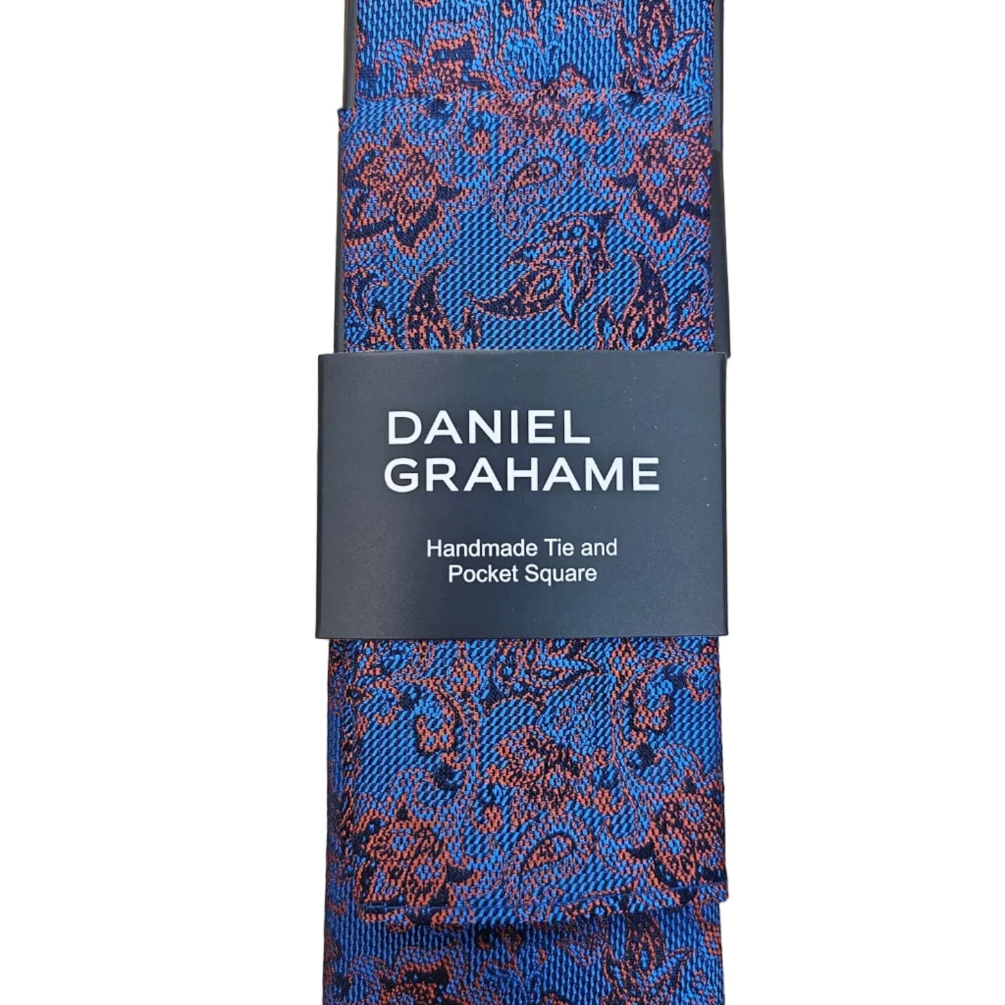 A Daniel Grahame patterned tie laid flat on a light wood surface, wrapped with a black paper band showing the brand name in white text.