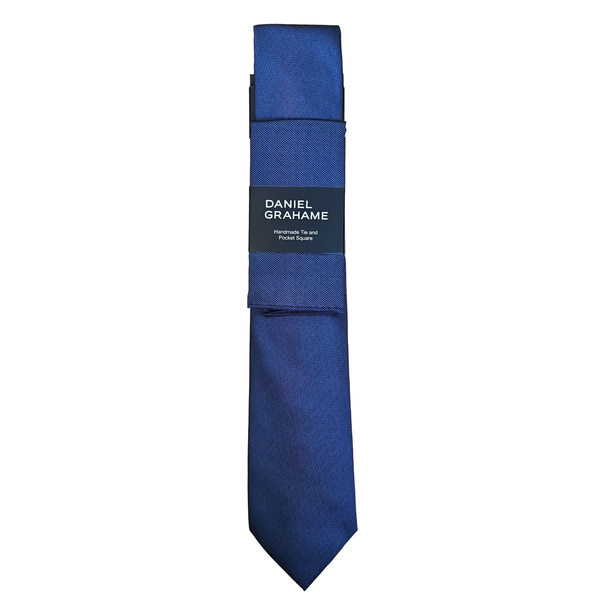 A folded navy blue necktie with a black paper band label reading 'DANIEL GRAHAME', placed on a light wood grain surface.