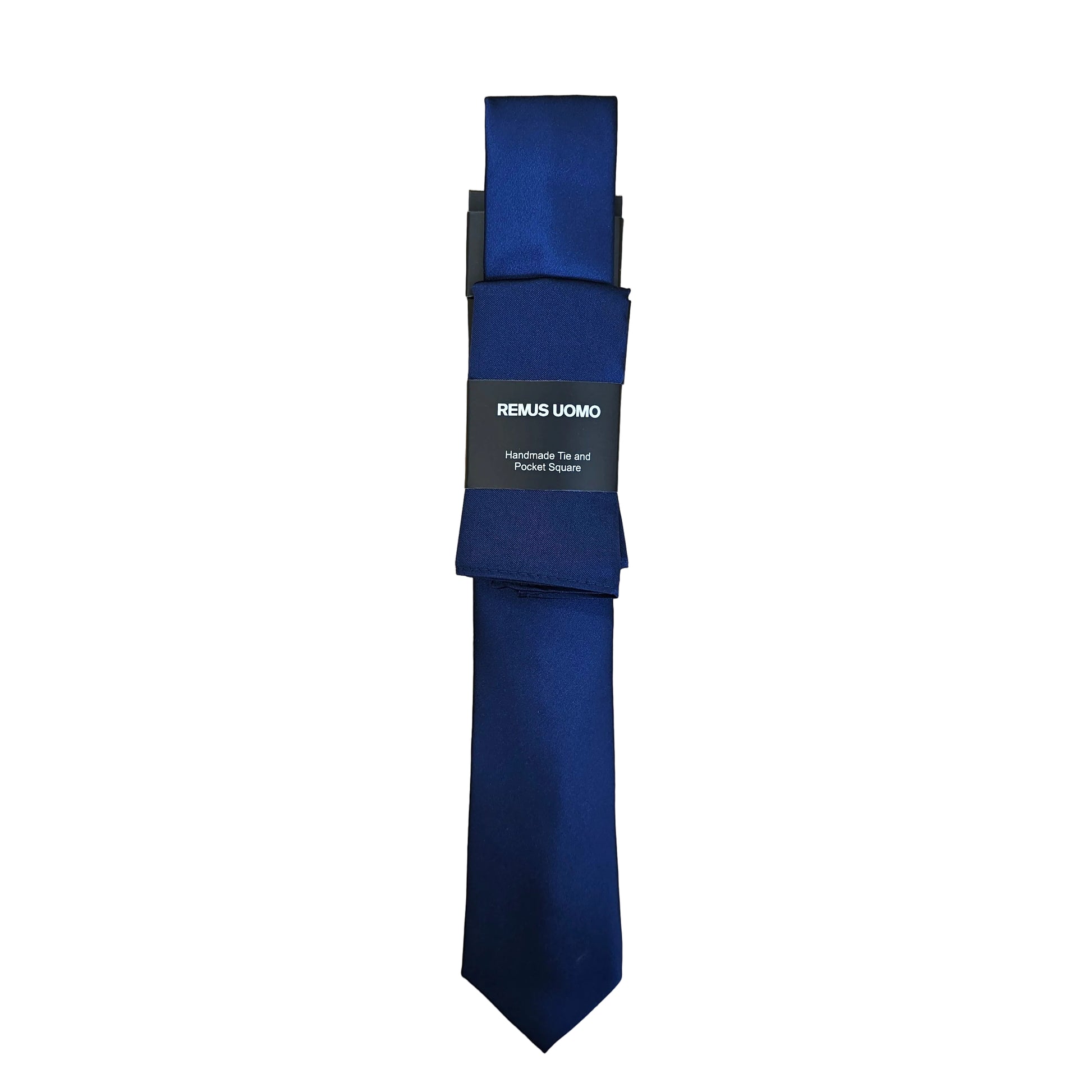A dark navy blue necktie with a black paper label that reads 'REMUS UOMO', laid flat on a light wood grain surface.