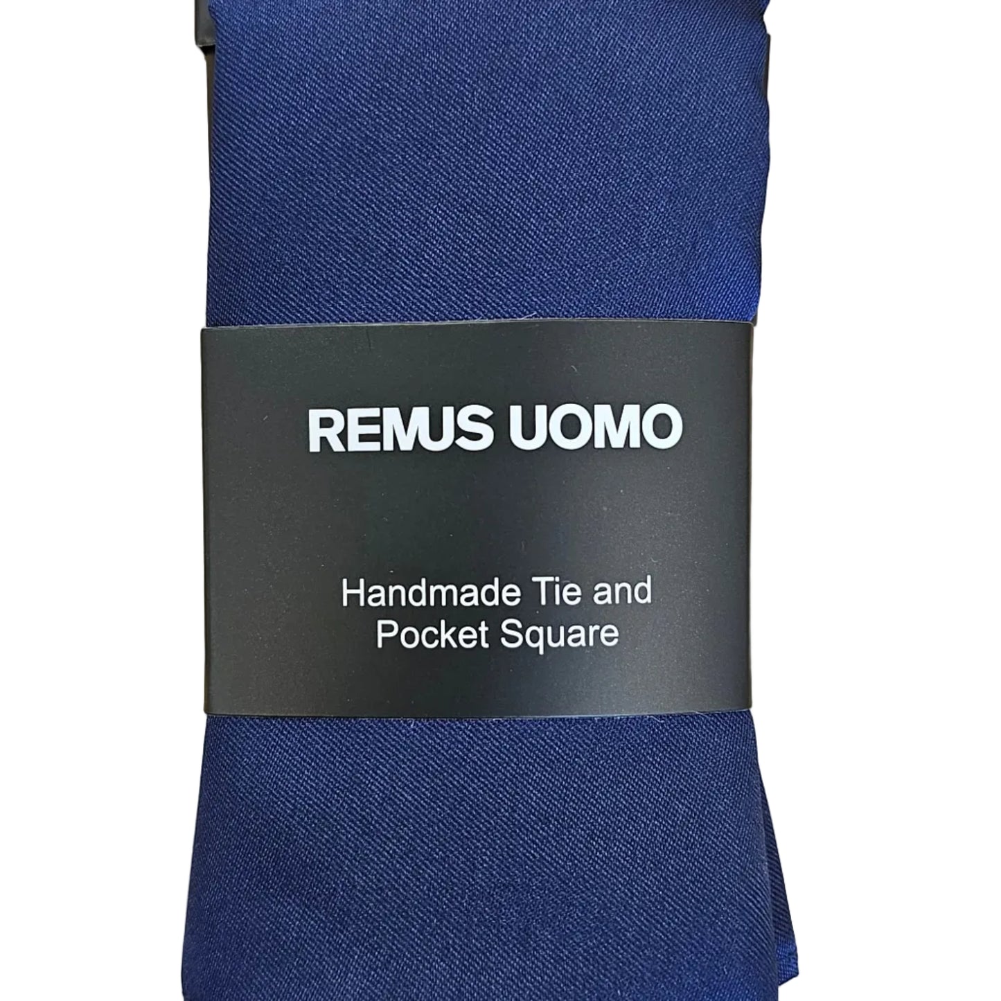 A navy blue square tie wrapped in a black paper band labeled 'REMUS UOMO', placed on a light wood grain surface.