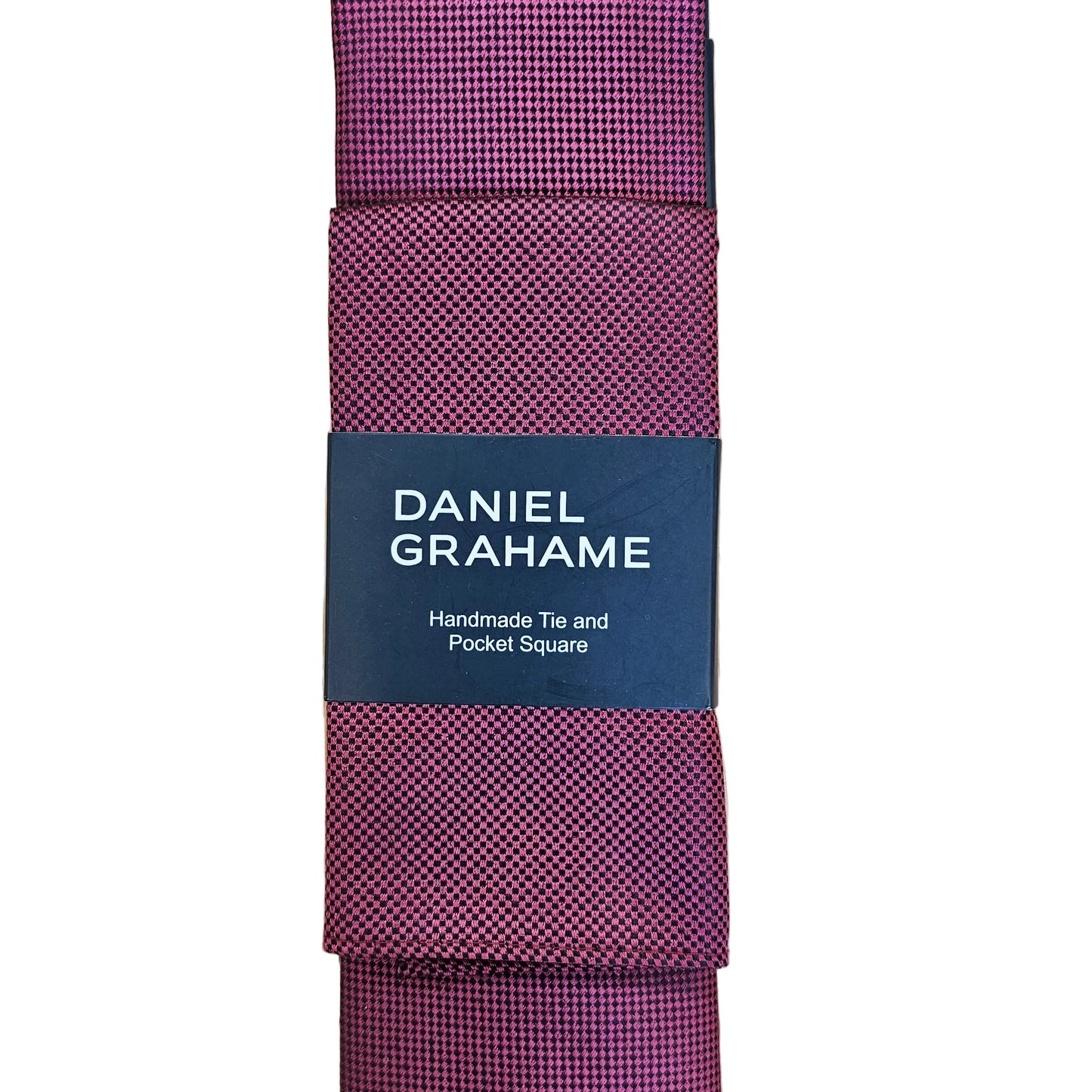 A folded red checkered necktie with a dark navy paper label that reads 'DANIEL GRAHAME Handmade Tie and Pocket Square', displayed on a light background.