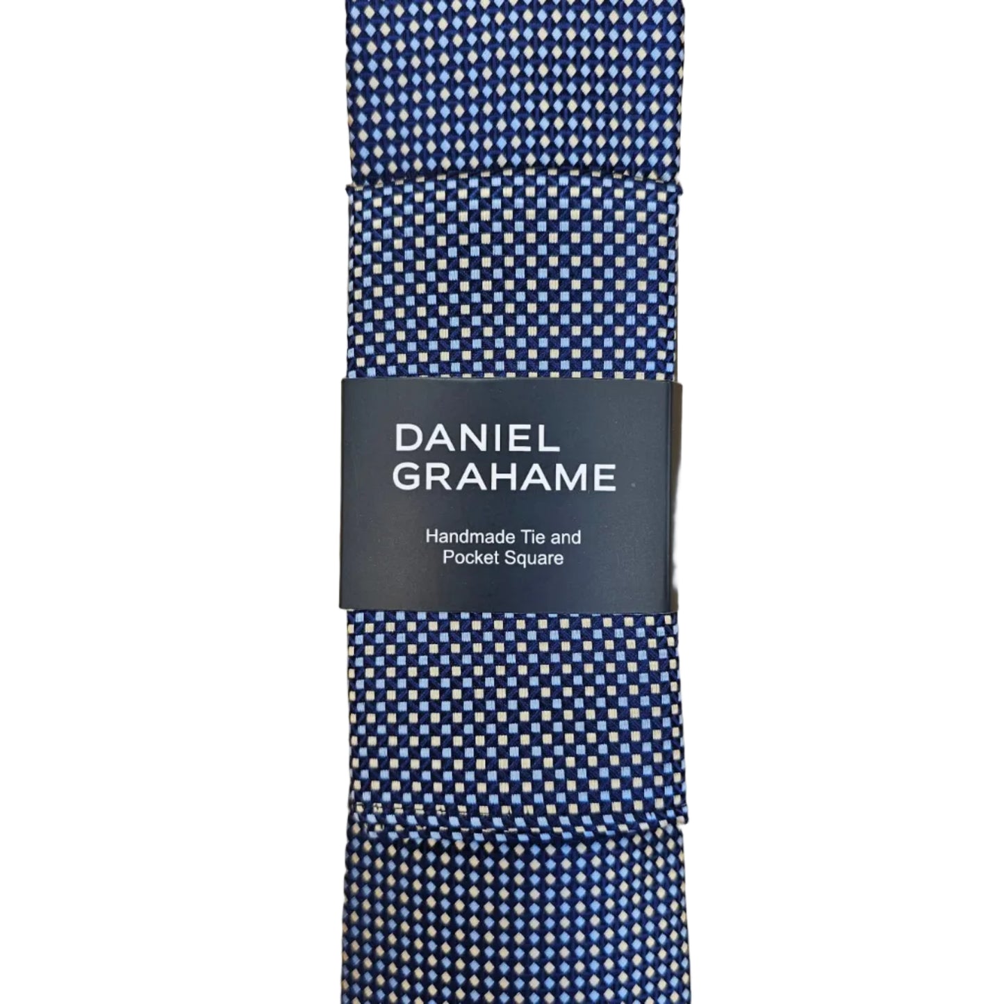 A folded Daniel Grahame tie with a blue and white micro-check pattern, wrapped in a black paper band with white text, set against a light wood grain background.