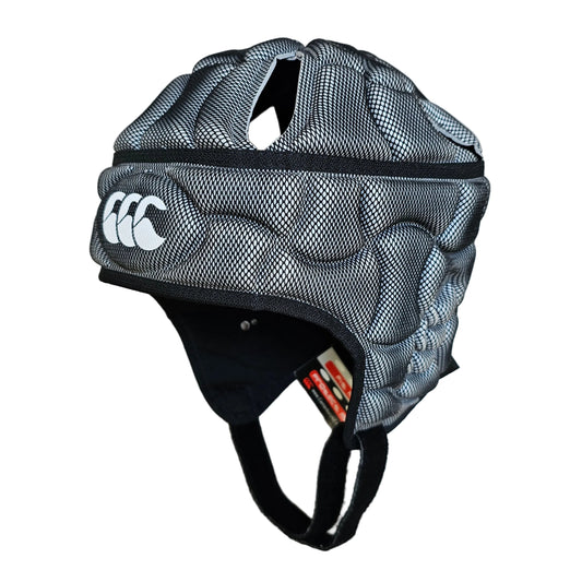 A black and gray mesh rugby helmet with white Canterbury logo, shown on a light wood floor.